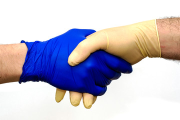 handshake of two hands in protective hygienic surgical gloves of different colors on the white background