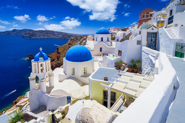 Fototapeta na wymiar Blue church domes and white houses in the beautiful Oia town on the Santorini island, Greece.