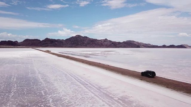 Guerrero Negro La Salinera. Drone Aerial Slow Fly Over of a Green SUV Driving Through The Salt Flats