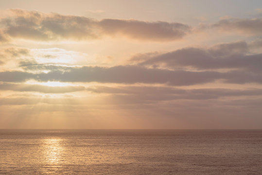 Beautiful tender sunset over the ocean. Clouds and sun over calm water. © garrykillian