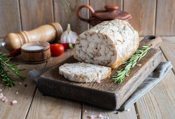 Delicious cut chicken roll on a wooden Board with a sprig of rosemary on a wooden table