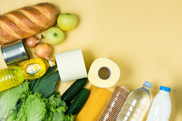 Essential fresh products lie on a green background. Eggs, greens, spaghetti, tomatoes, bread, milk, toilet paper, cookies, canned food. Food delivery covid-19 epidemic, Donation. top view. Copy space.