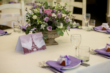 Wedding decor. A beautifully decorated festive table of fresh flowers in an antique vase, in purple shades
