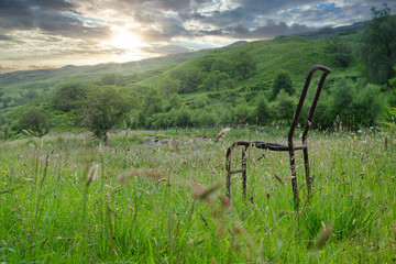 old metal chair on green grass in the mountains