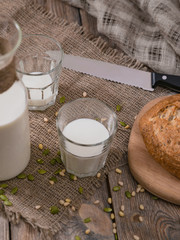 Milk and piece of bread on planked wooden table. Breakfast in the country on World Milk Day. Vertical shot from above.