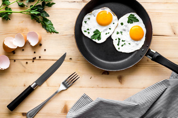 Fried eggs on frying pan on beige desk top-down