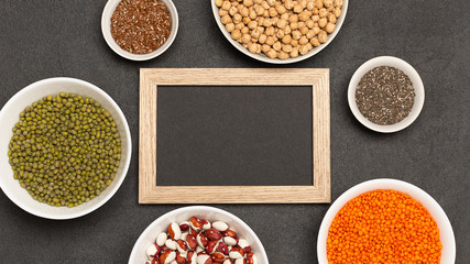 Menu background. Chalkboard with vegeterian protein sources on plates on dark, top view, copy space