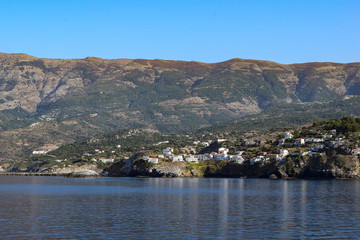 Greek towns on the island of Ikaria with mountains behind. Sailing through the Mediterranean Sea.