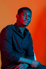 Face African American stylish man posing on the blue and red neon light background.