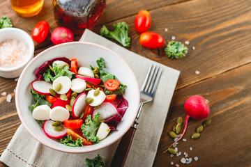 Salad with cherry tomatoes, radsh and mozzarella, lettuce mix