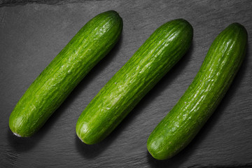 three cucumbers on a dark stone background vegatarian health fruit vegetables dark stone background.