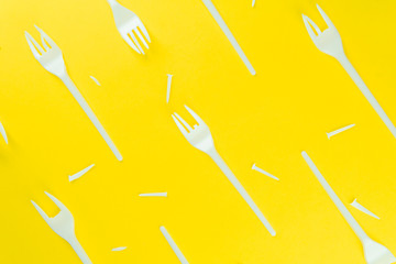A lot of broken plastic forks on a yellow background. The concept of environmental problems,...