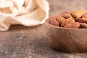 Almonds in a wooden bowl placed on a wooden table. almond nuts in bowl and space for text on the table