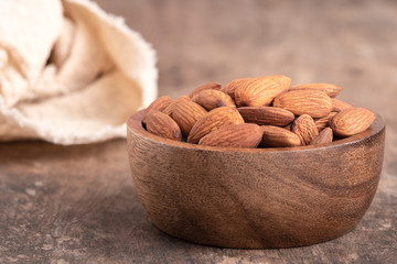 Almonds in a wooden bowl placed on a wooden table. almond nuts in bowl and space for text on the table