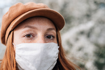 redhead woman in brown hat and protective mask close-up