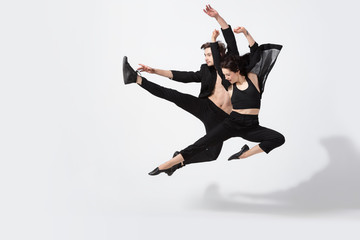 Fototapeta na wymiar Young and graceful ballet dancers in minimal black style isolated on white studio background. Art, motion, action, flexibility, inspiration concept. Flexible caucasian ballet dancers, weightless jumps