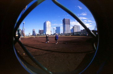 Fototapeta na wymiar People Playing On Sports Field Against Skyscrapers Seen Through Glass