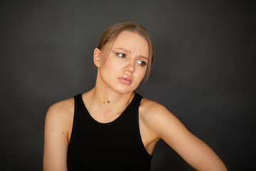beautiful, cute girl is upset on a dark background in the studio. emotions