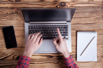 Workplace, male hands are typing on a laptop.