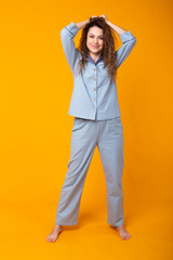 Young girl posing in pajamas on yellow background. Relax good mood, lifestyle and sleepwear concept.