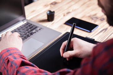 The workplace of the designer, men's hands work on a graphics tablet.