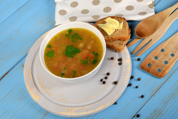 tripe soup in a white bowl next to bread and butter