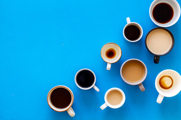 Cups of hot drinks on blue background from above frame copy space