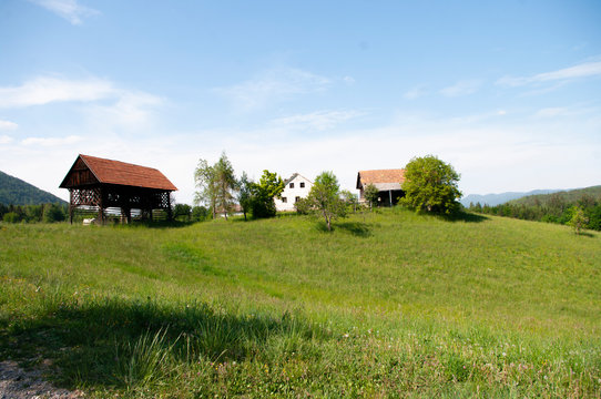 Wooden barn and old house on green field.