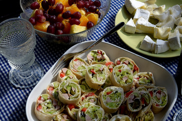 an empty glass, rolled up tortilla, fruit, cheese and wine on the terrace table