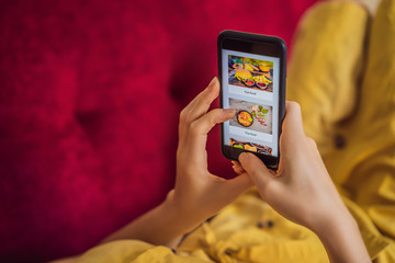 Young woman orders food for lunch online using a smartphone