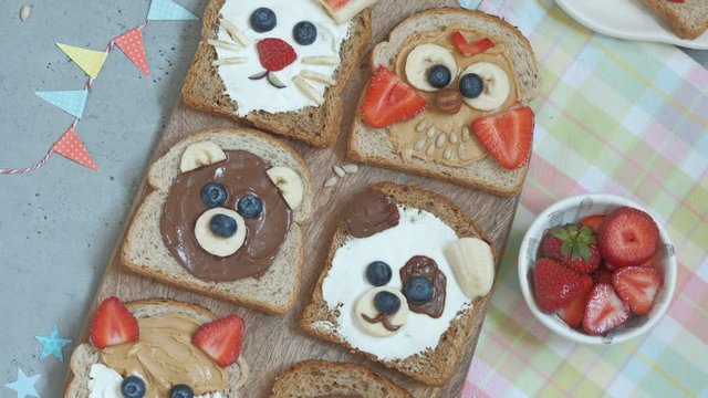 Funny animal faces toasts with spreads, banana, strawberry and blueberry