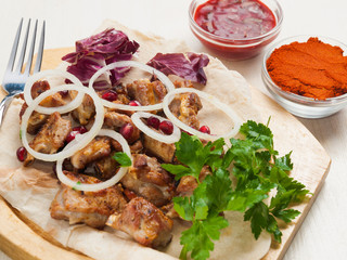 pieces of lamb on the bone with onions and sauces on a wooden Board