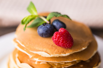 Pancakes with blueberries and raspberry on wooden background. Breakfast and traditional meal.