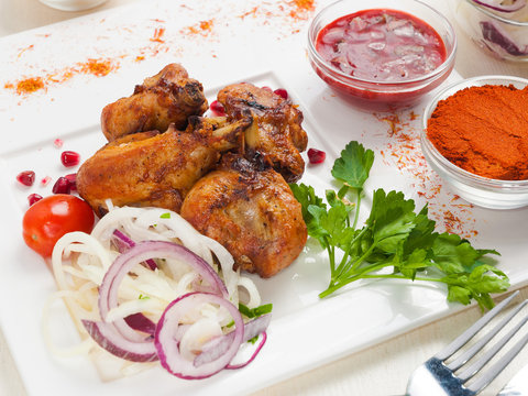 chicken skewers on bones on a white plate with vegetables and sauce