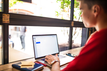 Young man skilled copywriter working distance on laptop computer while relaxing in coffee shop. Male developer web sites searching information via notebook