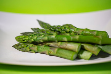 Banches of fresh green asparagus on white plate 
