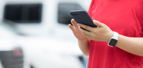 Hands using smartphone at outdoor parking lot