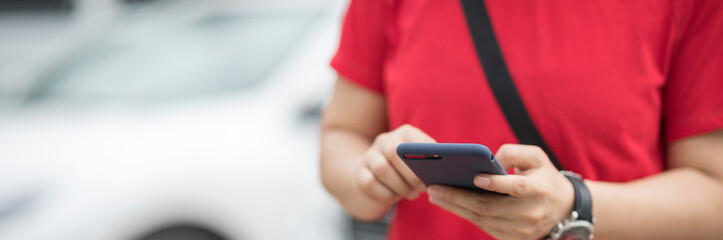 Hands using smartphone at outdoor parking lot