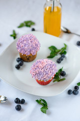 Delicious multi-colored cupcakes on a white plate on a white background.