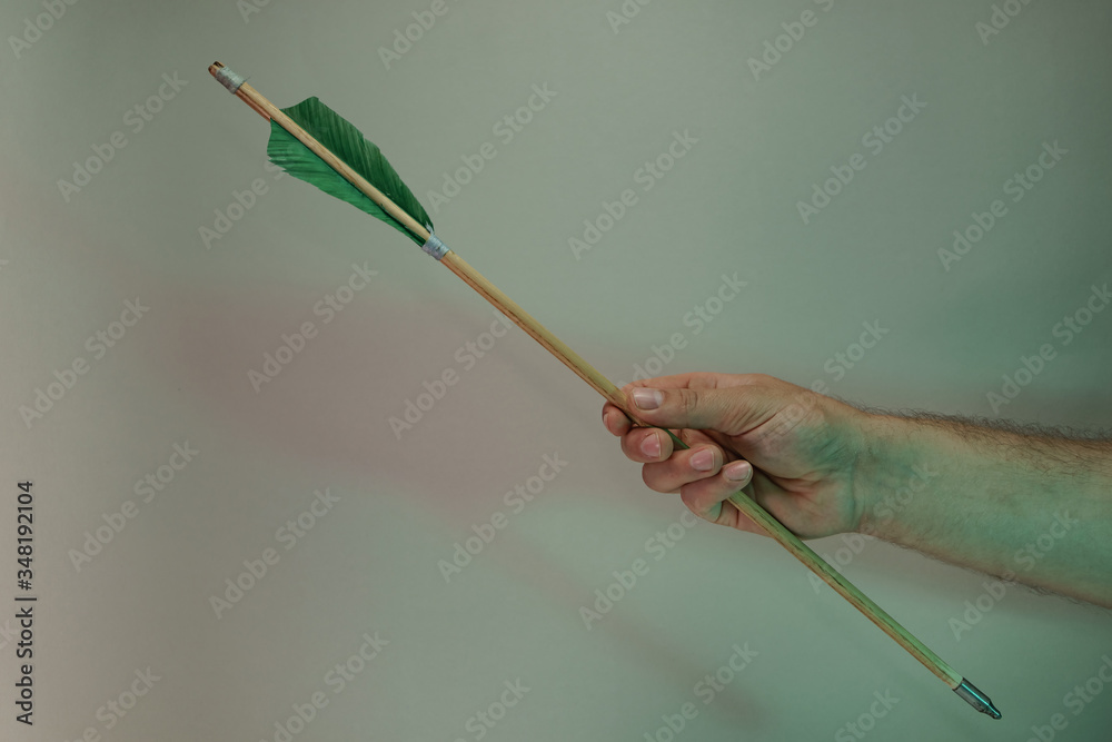 Poster Hand holding old green arrows in the color light. Beautiful old arrow minimal in neon light. Minimalism retro style concept. Background pattern for design.
