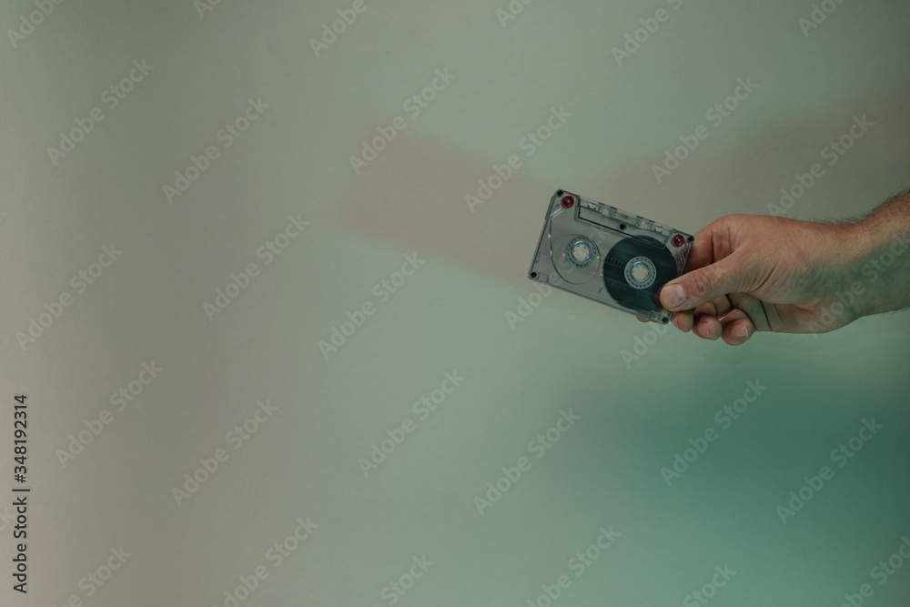 Poster Hand holding audio cassette tape in the color light. Beautiful minimal in neon light. Minimalism retro style concept. Background pattern for design.