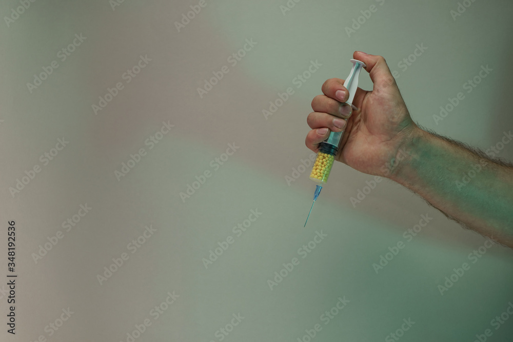 Aufkleber Hand holding creative syringe with yellow vaccine in the color light. Beautiful old minimal in neon light. Minimalism retro style concept. Background pattern for design.