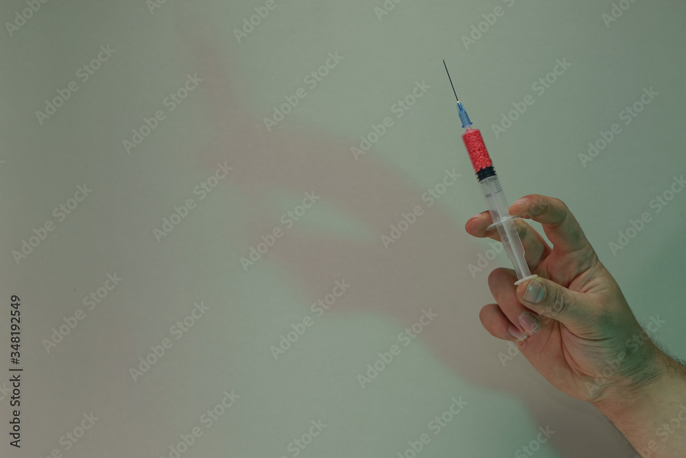 Poster Hand holding creative syringe with red vaccine in the color light. Beautiful. minimal in neon light. Minimalism retro style concept. Background pattern for design.
