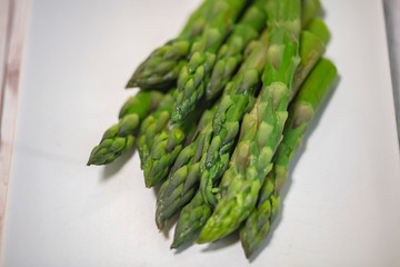 Banches of fresh green asparagus on white plate 