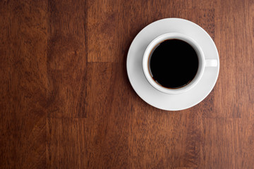 Top view of black coffee on wooden background.