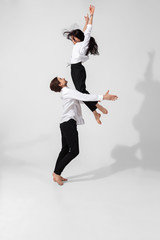 Fototapeta na wymiar Young and graceful ballet dancers in minimal black style isolated on white studio background. Art, motion, action, flexibility, inspiration concept. Flexible caucasian ballet dancers, weightless jumps