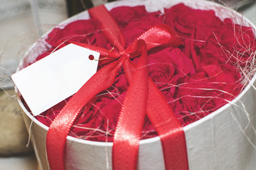 Rote Rosen in einer runden Scvhachtel mit roter Schleife und Blankoschild zum Beschriften-für Muttertag, Valentinstag, geburtstag usw.