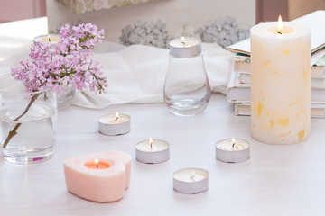 Fototapeta na wymiar Pastel room interior decor with burning hand-made candle, books, flowers. Cozy and relax concept.