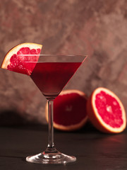 Red cocktail in a Martini glass. A grapefruit Martini. Hard light. Dark background. Red drink