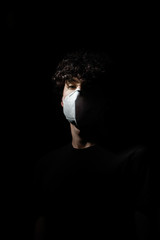 retrato iluminado de un solo lado de chico con mascarilla de proteción para virus